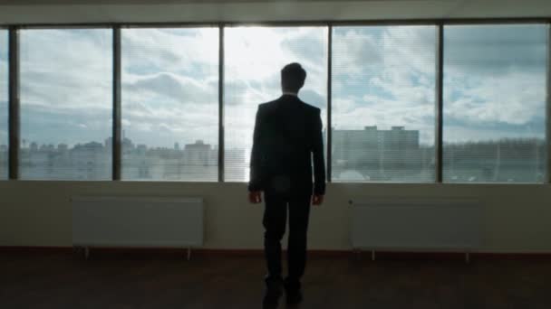 輝かしい眺め ビジネスモチベーション ビジネスマンは パノラマウィンドウの前に立って モダンなオフィスで朝 自然の照明 思考プロセス 4Kの遅い動き — ストック動画