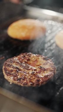 Sokak yemekleri, ızgarada hamburger pişirme, et ve çörek ızgarada kızartılır, hamburgerler, dikey video, 4k süper yavaş çekim..