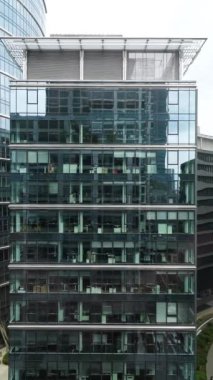 Şehir manzarası modern ofis binası, iş merkezi, trafik binanın cam cephesine yansıyor, ofis içleri camdan görünüyor, dikey video, şehir merkezi..