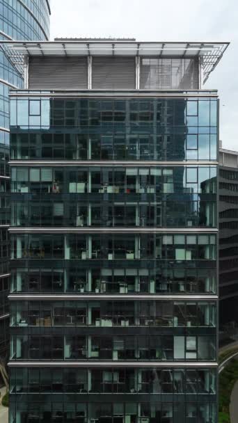 近代的なオフィスビル ビジネスセンター トラフィックのシティスケープビューは 建物のガラスファサードに反映され 垂直ビデオ ダウンタウンを介してオフィスのインテリアビュー — ストック動画
