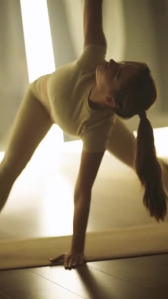 ウェルネス スポーツウーマンは部屋でヨガをしている 柔軟な女性はヨガの要素 垂直ビデオでストレッチを行います — ストック動画