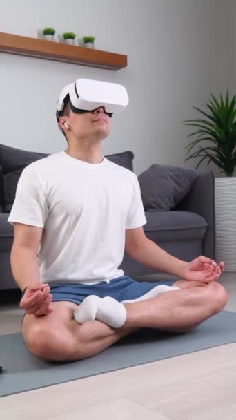 バーチャルリアリティメガネの陽気な男はリビングルームで瞑想し 現代技術と拡張現実 垂直ビデオ — ストック動画