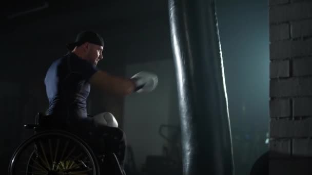 Tekerlekli Sandalyedeki Engelli Bir Dövüşçünün Portresi Kum Torbasında Yumruklar Boks — Stok video