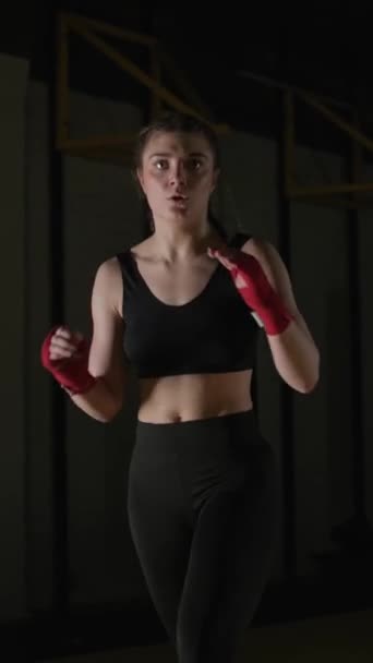 女性戦闘機は彼のキックを訓練し ボクシングジムでトレーニング スポーティな女性は一連のキック 垂直ビデオを訓練します — ストック動画