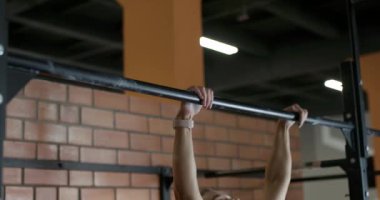 Genç bir kadın barfiks çekiyor, spor salonunda antrenman günü, güçlü vücut, ağır çekim..
