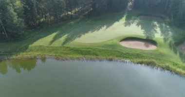 Yazın yeşil tarlalar, gölet üzerinde uçan, orman bölgesinde golf sahası manzarası, golf kulübü, orman ve göl kenarındaki yeşil çimlerin manzarası..