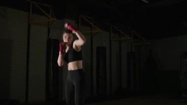 Sportif kadın dövüşçü tekmelerini boks salonunda eğitiyor..