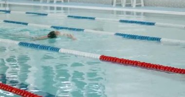 Genç sporcu havuzda yüzer, adam suda yüzer ve antrenman yapar, ağır çekimde..