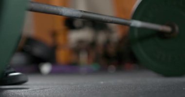 Spor salonundaki kadın, halteri kaldırıyor, ağırlıklı kas antrenmanı yapıyor, çapraz formda..