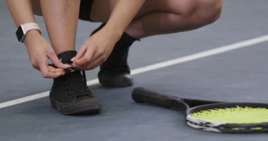 Spor ayakkabılarına ayakkabı bağlayan genç bayan tenisçi, antrenman günü..