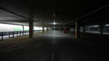 Boş yeraltı otoparkında yürüyün. Beton duvarları, beton tüneli ve kromakey şablonu olan bir ofis binasının otoparkında düzgün kamera hareketleri yapın..