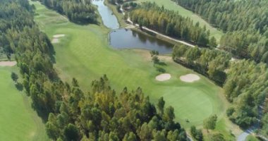 Yazın güneşli bir günde yeşil alanlar, orman bölgesindeki golf sahasının havadan görünüşü, golf kulübü, orman ve göl kenarındaki yeşil çimlerin manzarası..