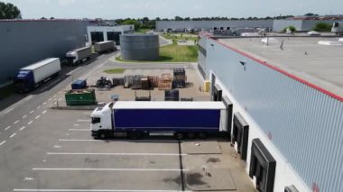 Varşova, Polonya - 29 Haziran 2024: Konut alanı yakınlarındaki depolar, lojistik merkezi, depo binaları, kargo taşımacılığı, hava manzaralı çok sayıda kargo römorku ve kamyon manzarası.