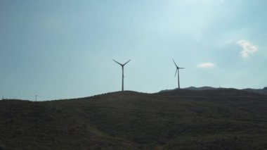 Tepe bölgelerindeki rüzgar tarlası, dönen bıçaklar, alternatif yenilenebilir enerji kaynakları, rüzgar türbinlerinin manzarası..