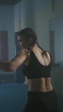 Beyaz kadın dövüşçü boks salonunda yumruklarını ve savunmalarını eğitiyor. Kız hızlı ve dikey bir şekilde saldırıyor..