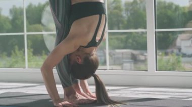 İyilik, genç bir kadın ışıkla dolu beyaz bir odada esneme ve yoga yapıyor, kız yoga yapıyor ve büyük pencerenin yanında elementler sergiliyor..