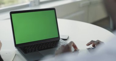 Ofis, birinci şahıs görünümü, koyu tenli iş adamı yeşil ekranlı bir dizüstü bilgisayarda çalışıyor, ekranda istatistikleri gösteriyor, eş zamanlı çalışma, kroma anahtar şablonu.