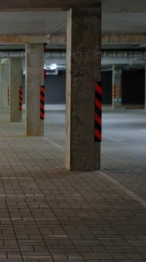 Dikey video, boş bir yeraltı otoparkının durağan arka planı beton duvarlı bir ofis binası, beton tünel, şablon..