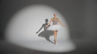 Performans, pembe etekli bir dansla zarif bir balerin ve beyaz arka planda dramatik koreografik öğeler sergilemek, rüzgarlı ve güzel bir dans..