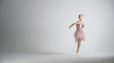 Performans, pembe etekli bir dansla zarif bir balerin ve beyaz arka planda dramatik koreografik öğeler sergilemek, rüzgarlı ve güzel bir dans, yavaş çekim..