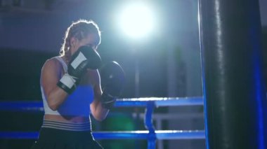 Sportif bir kadın kum torbasını yener, boks salonunda antrenman günü, boksör onun yumruklarını eğitir, güçlü bir vücut, süper yavaş çekim.