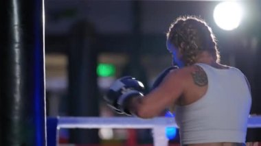 Kadın dövüşçü kum torbasını yener, boks salonunda antrenman günü, boksör tekmelerini ve yumruklarını eğitir, güçlü bir vücut, süper yavaş çekim.