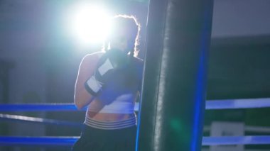 Süper yavaş çekim, sportif kadın kum torbasını yener, boks salonunda antrenman günü, boksör yumruklarını eğitir, vücudu sağlamdır..