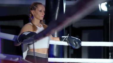 Süper yavaş çekim, ringin kenarında duran bir kadın dövüşçünün portresi, sıkı antrenman ve idman için hazırlanıyor, kadın gücü..