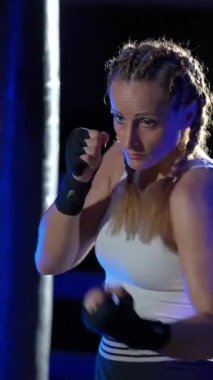 Kadın boksör yumruklarını eğitiyor, boks salonunda antrenman yapıyor, kadın bir dizi yumruk, ön görüş, dikey video..