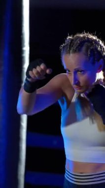 Kadın boksör yumruklarını eğitiyor, boks salonunda antrenman yapıyor, kadın bir dizi yumruk, ön görüş, dikey video..