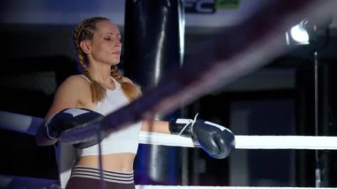 Ringin kenarında duran bir kadın dövüşçünün portresi, sıkı antrenman ve idman için hazırlanıyor, derin nefes alıyor, kadın gücü.