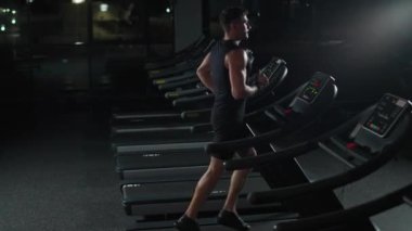 Belarus, Minsk - 17 Ocak 2021: Koşu bandında koşan atletizm koşucusu, spor salonunda aerobik egzersiz ve dayanıklılık eğitimi, gece eğitiminde motivasyon, 4k yavaş çekim.