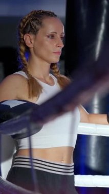 Yavaş çekim, ringin kenarında duran bir kadın dövüşçünün portresi, sıkı eğitime hazır, dikey video, kadın gücü.