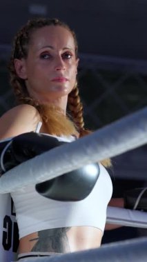 Yavaş çekim, ringin kenarında duran bir kadın dövüşçünün portresi, sıkı antrenman, dikey video, kadın gücü..