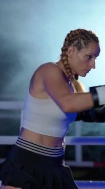 Sportif bir kadın kum torbasını yener, boks salonunda antrenman günü, boksör tekmelerini ve yumruklarını eğitir, güçlü bir vücudu vardır..