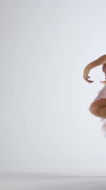 Pembe etekli balerin, beyaz arka plan, rüzgarlı ve güzel dans ve yavaş dikey video üzerinde dramatik dans eder..