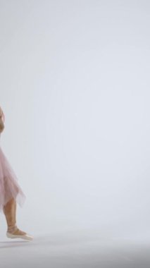 Yavaş çekim, pembe etekli balerin beyaz arka planda, rüzgarlı ve güzel dans, dikey video.