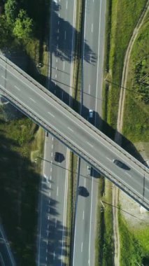 Dikey video, ormanın yakınındaki otoyolda uçuş, ormanın ve yolun yükseklikten görünüşü, otoyolda trafik, doğa manzarası..