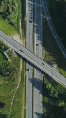Ormanın yakınındaki otoban üzerinde uçuş, ormanın ve yolun yükseklikten görünüşü, otoyoldaki trafik, doğa manzarası, dikey video..