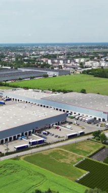 Varşova, Polonya - 25 Haziran 2024: Dikey video, lojistik merkezi, depo binaları yakınlarındaki çok sayıda kargo römorku ve kamyon manzarası, kargo taşımacılığı, hava manzarası.