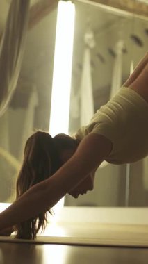 Sakin bir ruh hali, aynalı bir odada yoga yapan genç bir kadın, yoga öğeleriyle esneme hareketleri yapıyor, yavaş çekim..