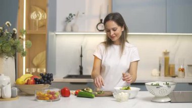 Neşeli kadın avokado, kırmızı biber ve domatesli sebze salatası, ev mutfağı ve sağlıklı yemek hazırlıyor..