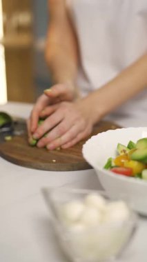 Dikey video, kadın sebze salatası hazırlıyor, avokadoyu küçük parçalara ayırıyor, sağlıklı yiyecekler, yavaş çekim..