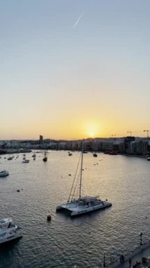 Malta, Valletta - 22 Mart 2025: Güney Avrupa, eski kasaba yakınlarındaki güzel günbatımı manzarası, körfez manzarası, mimari ve yat limanı, dikey video manzarası, Malta, Valletta durağan arka plan