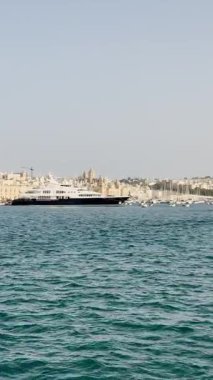 Malta, Valletta - 23 Mart 2025: Güney Avrupa, eski kent yakınlarındaki büyük yatın güzel manzarası, mimari ve yat limanı, dikey video manzarası, körfez manzarası, Valletta durağan arka plan.