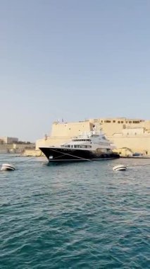 Malta, Valletta - 23 Mart 2025: Güney Avrupa, eski kent yakınlarındaki büyük yatın güzel manzarası, mimarlık ve yat limanı, dikey video manzarası, körfez manzarası.