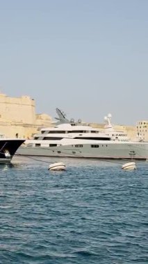 Malta, Valletta - 23 Mart 2025: Bay, eski kent, mimarlık ve yat limanı yakınlarındaki büyük yatların manzarası, dikey video manzarası.