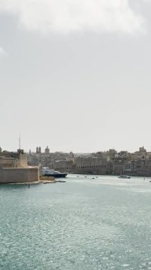 Malta, Valletta - 23 Mart 2025: Körfez manzarası, kasabanın yakınındaki yatlar, eski kasaba mimarisi ve yat limanı, dikey video manzarası, Valletta körfezi statik arka planı.