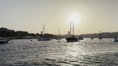 Malta, Valletta - 23 Mart 2025: Güney Avrupa, güzel günbatımı manzaralı yatlar ve eski kasaba, mimarlık ve yat limanı, Malta, Valletta gün batımında, durağan arka plan.