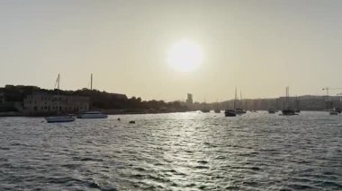 Malta, Valletta - 23 Mart 2025: Güzel bir gün batımı manzaralı yat ve kasaba, mimarlık ve yat limanı, Malta, Valletta gün batımında, durağan arka plan.